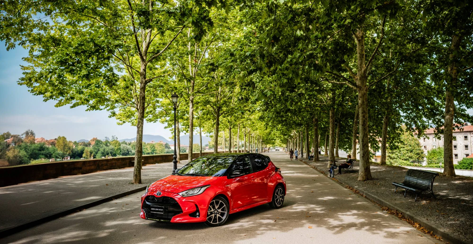Una Toyota Yaris rossa sul viale alberato delle Mura di Lucca