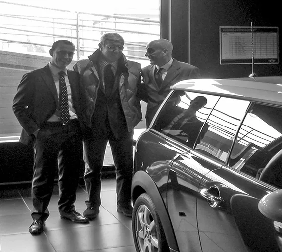 Tre persone nello showroom accanto a una Mini