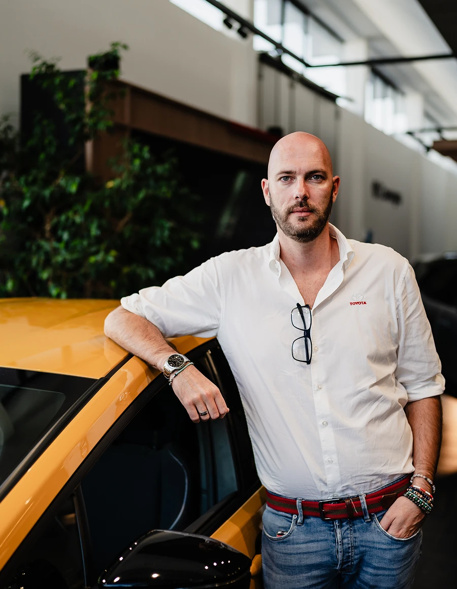 Un consulente Lucar appoggiato a una Toyota gialla in showroom