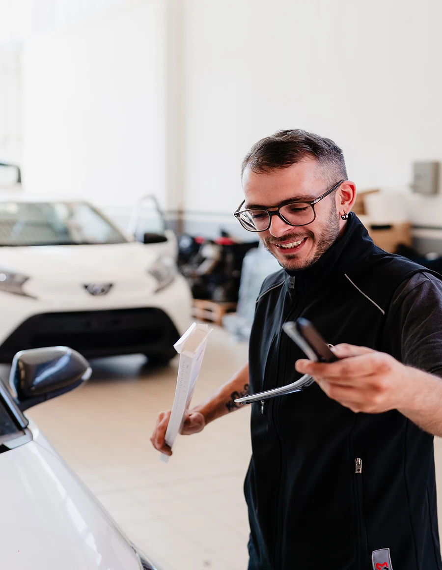 Un tecnico Lucar sorridente accanto a una Toyota in officina